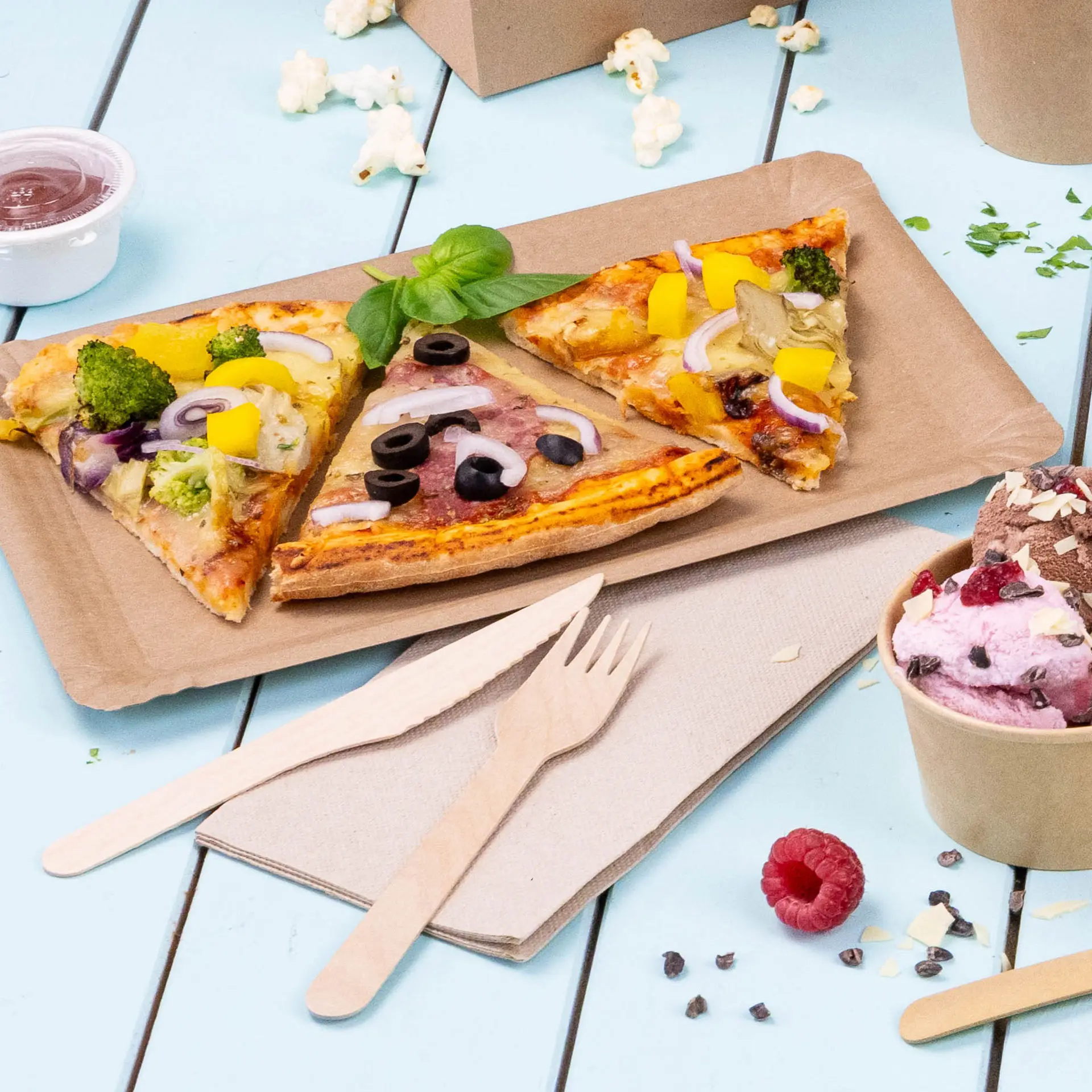 Afbeelding van drie pizzapunten op een bruin papieren dienblad, met houten bestek en een beker ijs in de buurt.