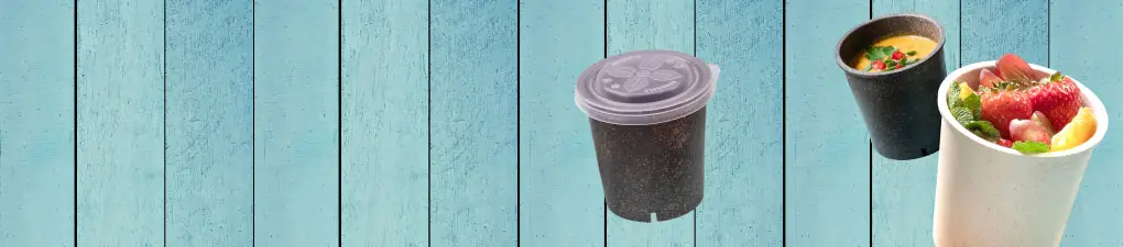 Groen cartoonfiguur met zonnebril, houdt een drankje en een telefoon vast, met komkommers op een blauwe houten achtergrond.