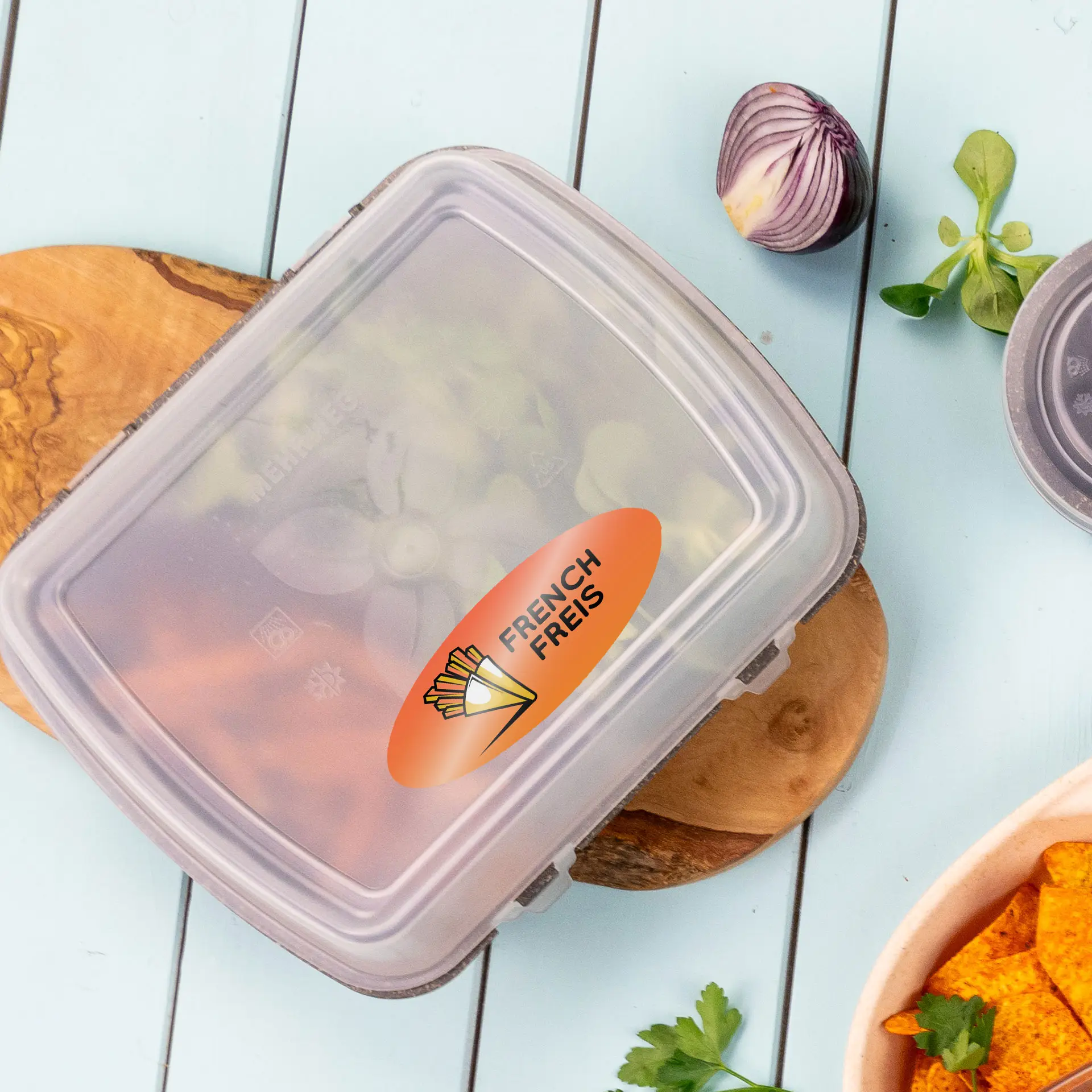 Duidelijk ovaal etiket met de tekst "FRENCH FRIES" op een container, omringd door verse ingrediënten op een houten plank.