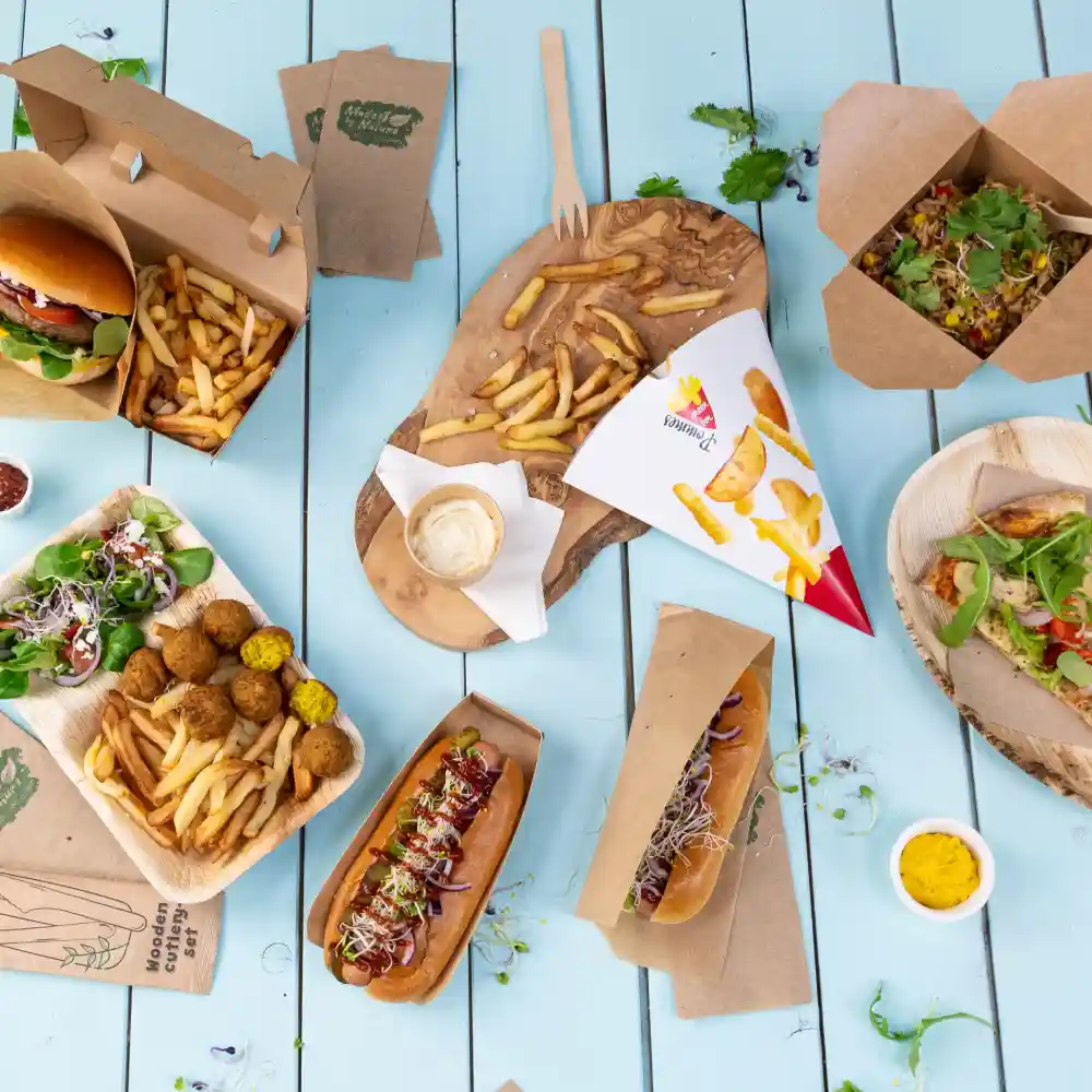 Verscheidenheid aan fastfood, waaronder burgers, hotdogs, friet, salades en falafel, geserveerd op houten en papieren trays.