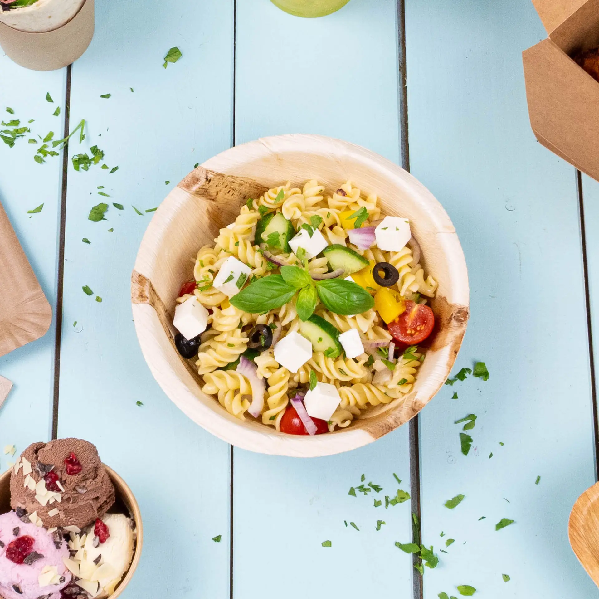 Een grote ronde schaal van palmblad gevuld met gemengde salade; kleinere palmbladschaaltjes in de buurt bevatten rijst en andere voedingsmiddelen.