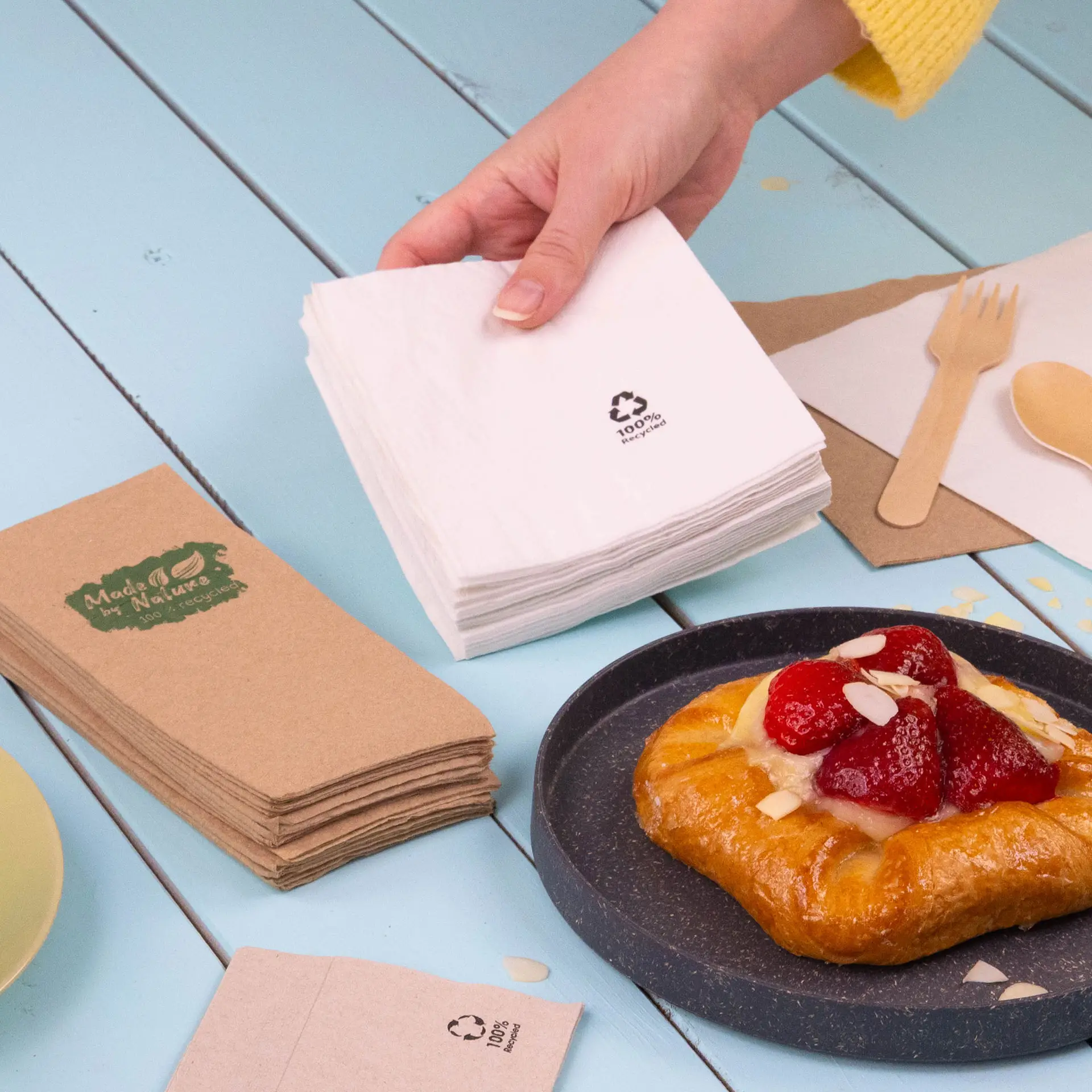 Twee vierkante cocktailservetten, één wit en één lichtgrijs, beide van gerecycled papier met recycling symbolen.