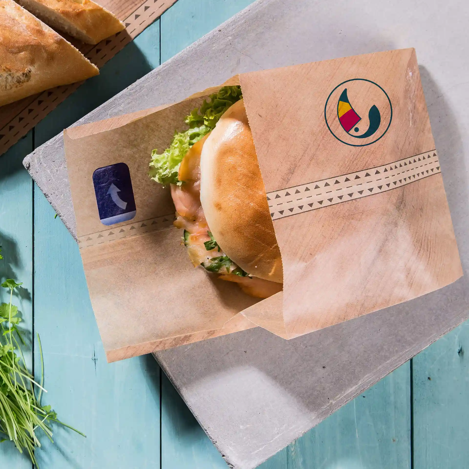 Bruine op maat gemaakte burgerhuls met kleefsluiting, met een burger met sla op een blauwe houten ondergrond.