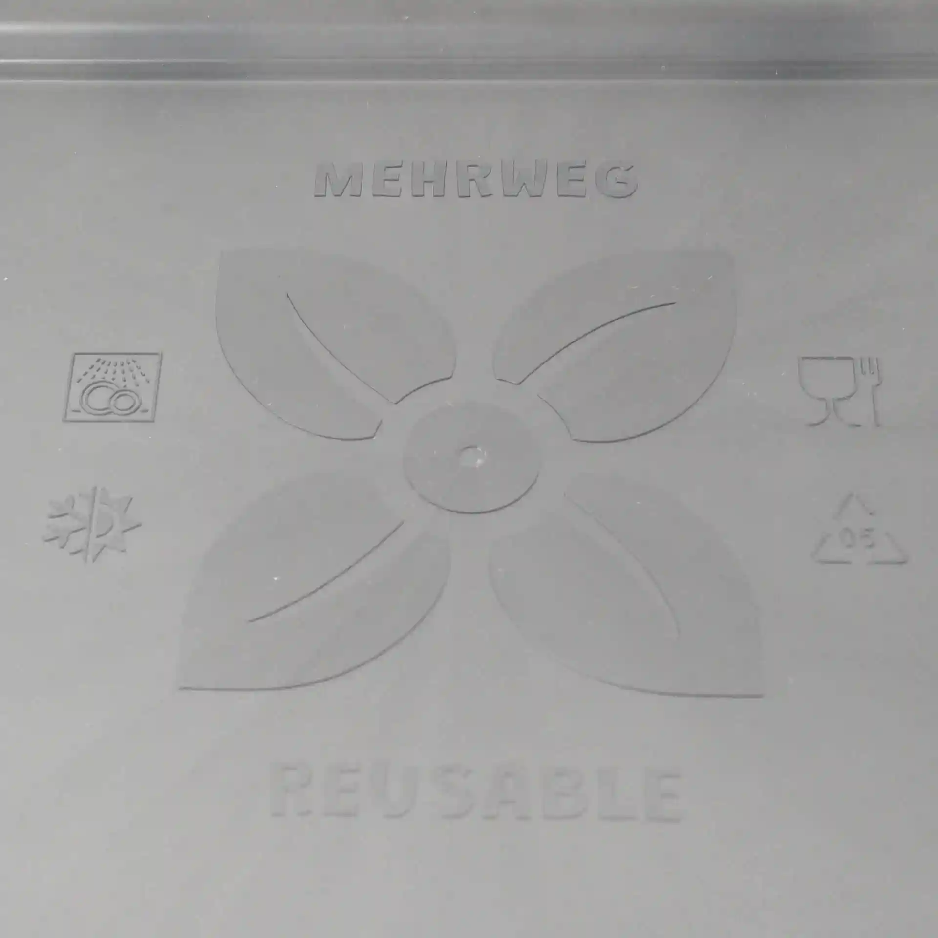 Schematische tekening van een grijze herbruikbare deksel met bladdesign en verschillende symbolen op een effen achtergrond.