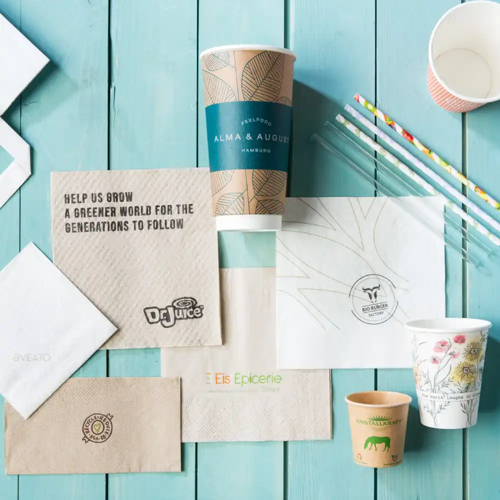 Een verscheidenheid aan bedrukte verpakkingsmaterialen, waaronder cups, servetten en rietjes op een houten oppervlak.