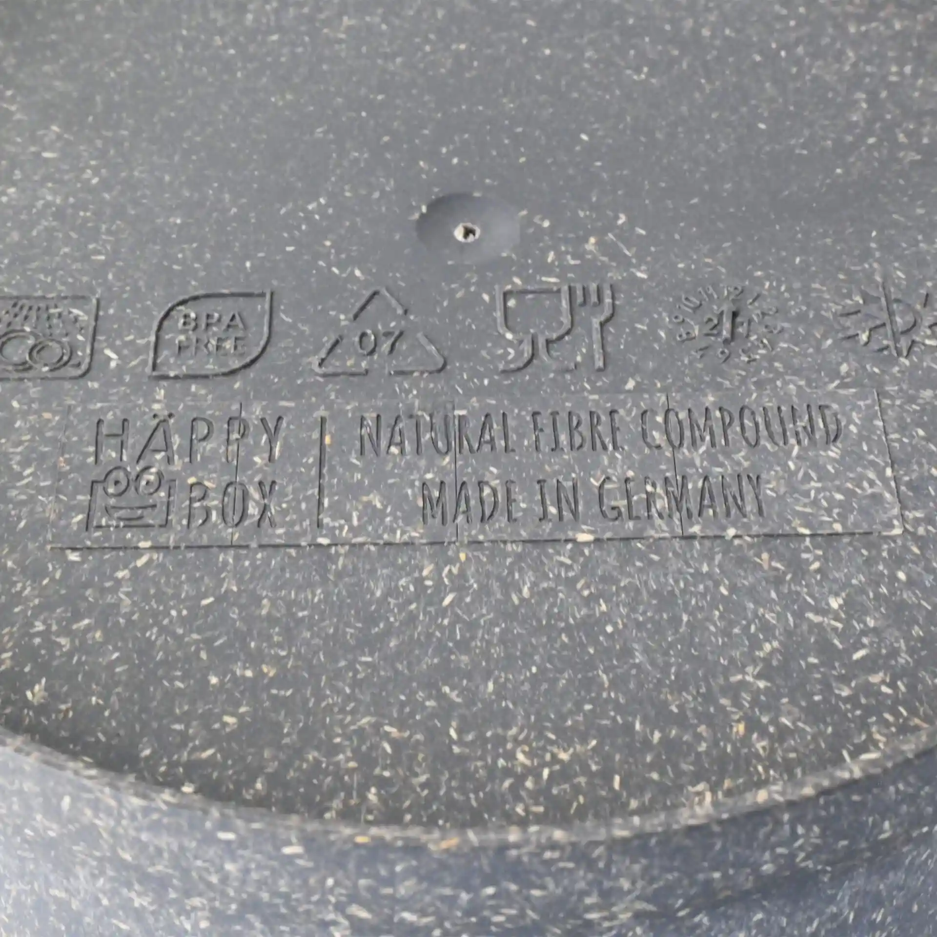 Label met symbolen zoals BPA-vrij, recycling en voedselveiligheid op een grijze herbruikbare kom van biocomposiet.