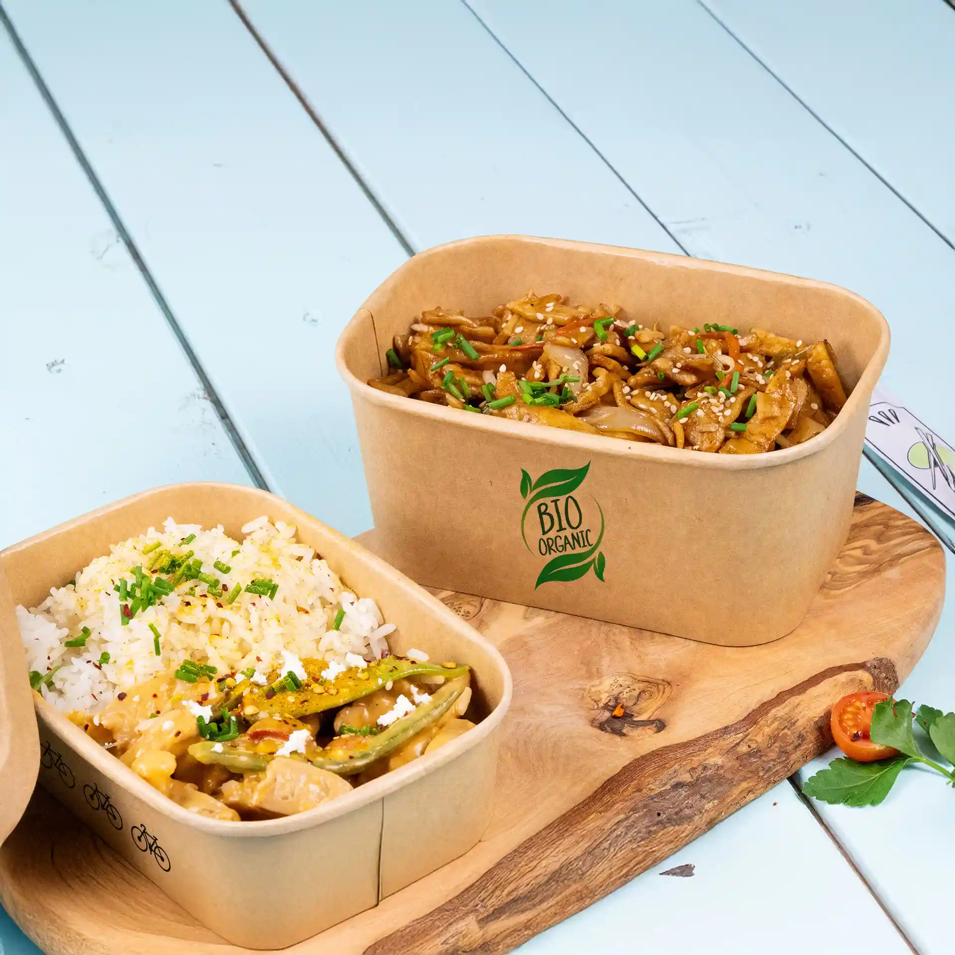 Rechthoekige bruine saladeschalen met rijst en noedels, weergegeven op een houten plank tegen een lichtblauwe achtergrond.