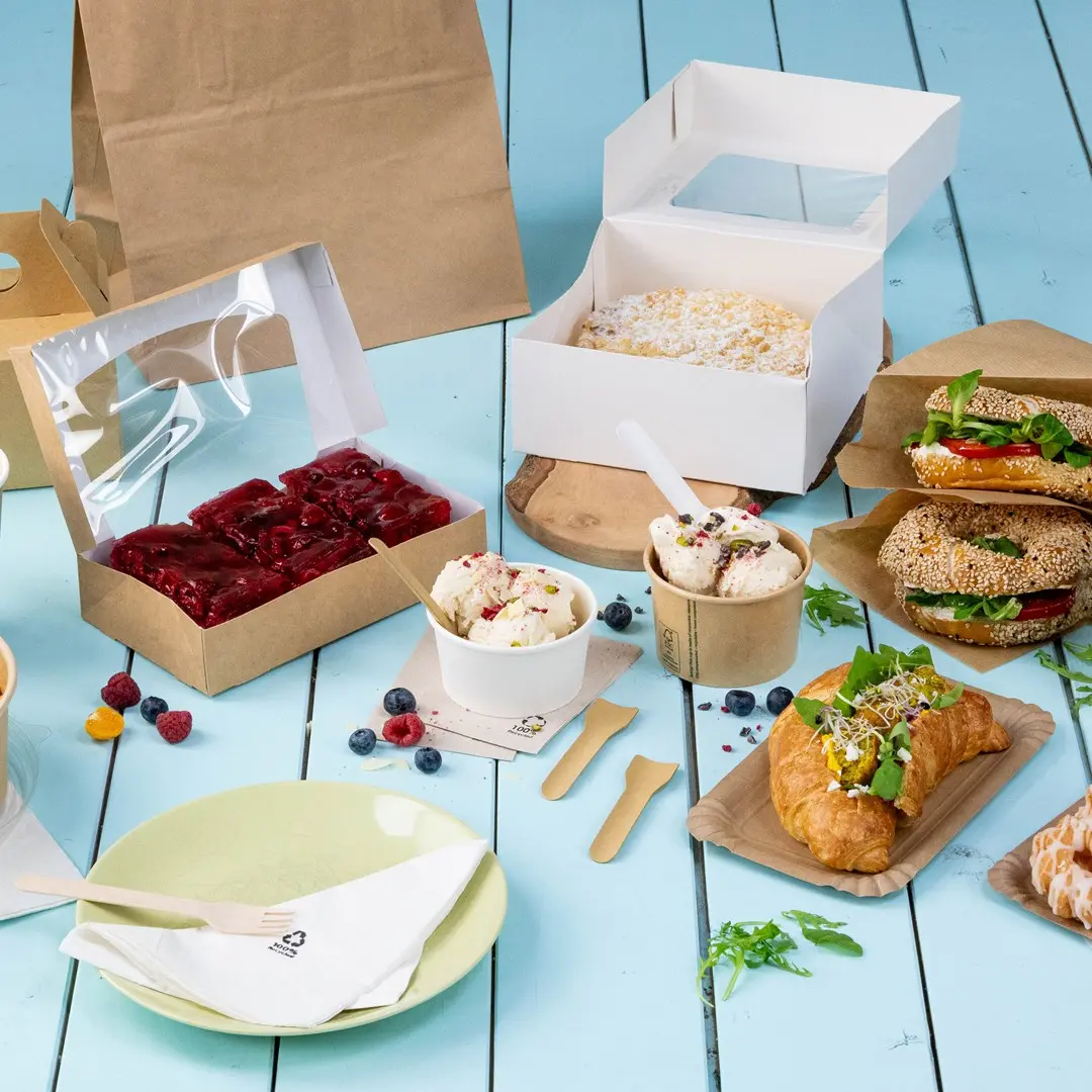 Diverse voedingsmiddelen, waaronder sandwiches, desserts en ijs in verschillende containers op een blauwe houten ondergrond.