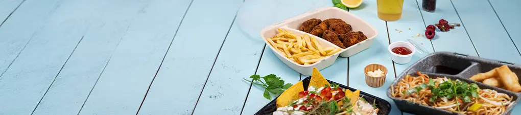 Groene cartoonchef met een lepel naast een voedselcontainer; blauwe houten achtergrond.