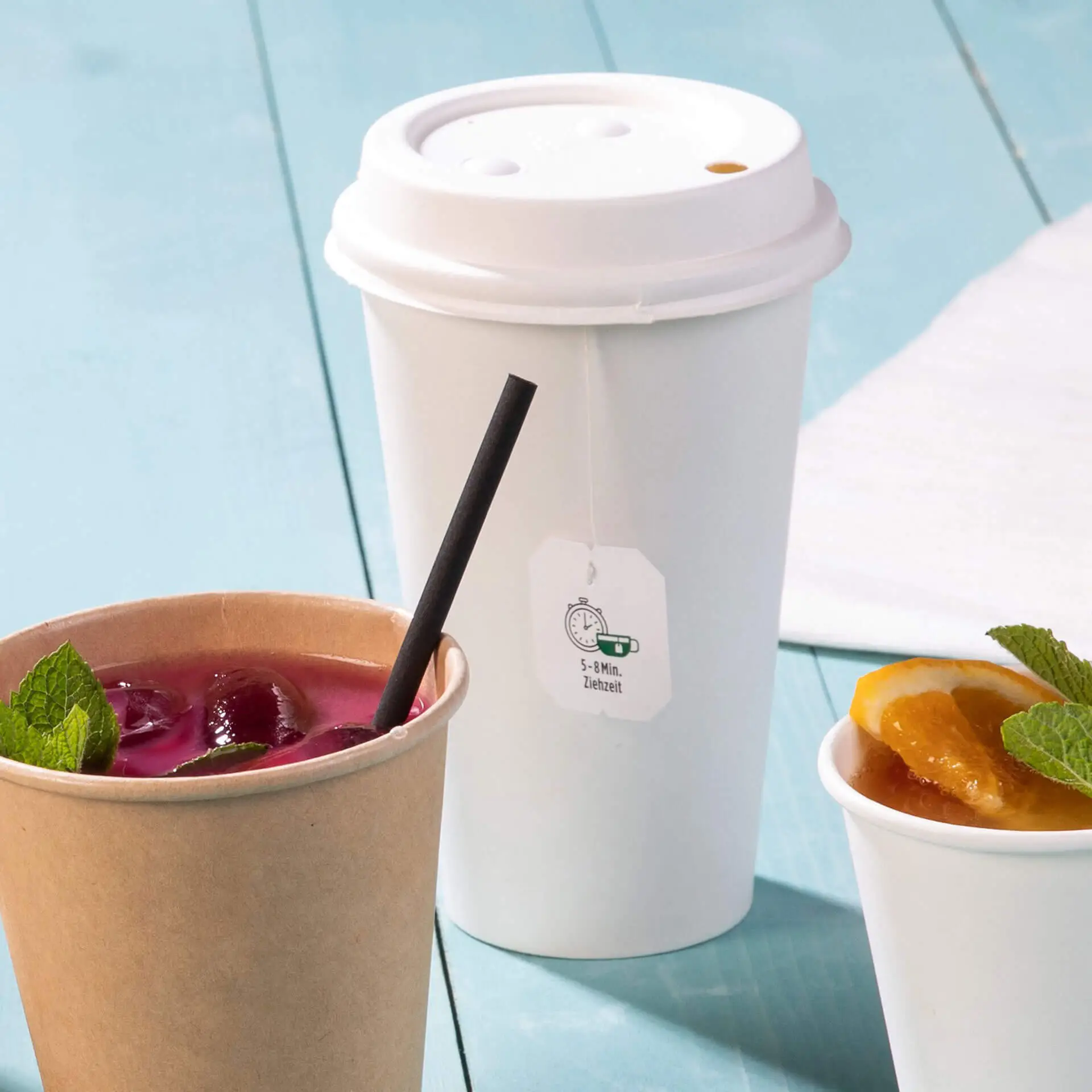 Eenvoudig wand wit papieren bekertje met PLA-coating, geschikt voor warme en koude dranken, naast een papieren bekertje met drankje en fruit.
