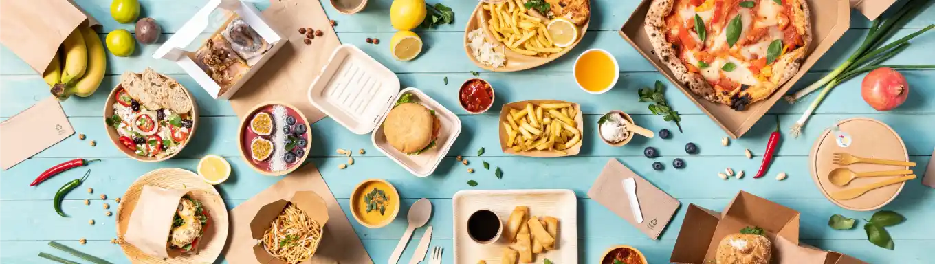 Een verscheidenheid aan voedselitems op een blauwe ondergrond, waaronder pizza, salades, hamburgers en desserts in verpakkingen.