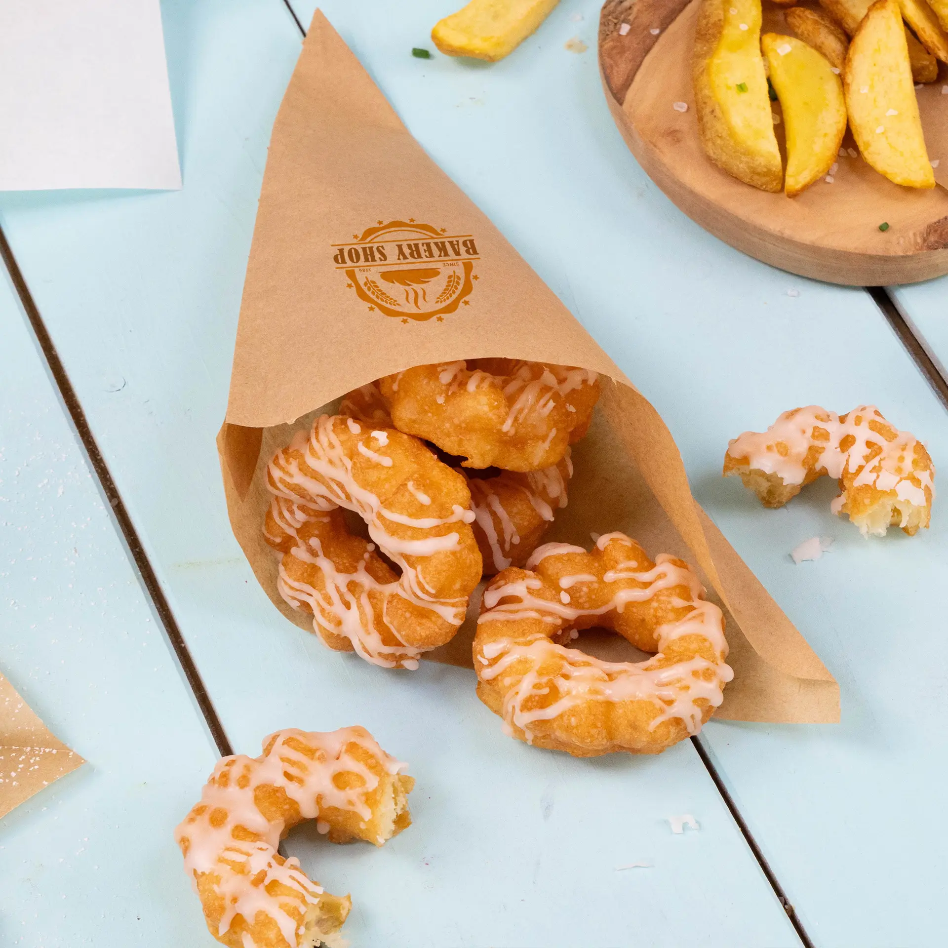 Bruine papieren puntzak met geglazuurde donuts, met een zichtbaar logo aan de zijkant, op een blauwe ondergrond.