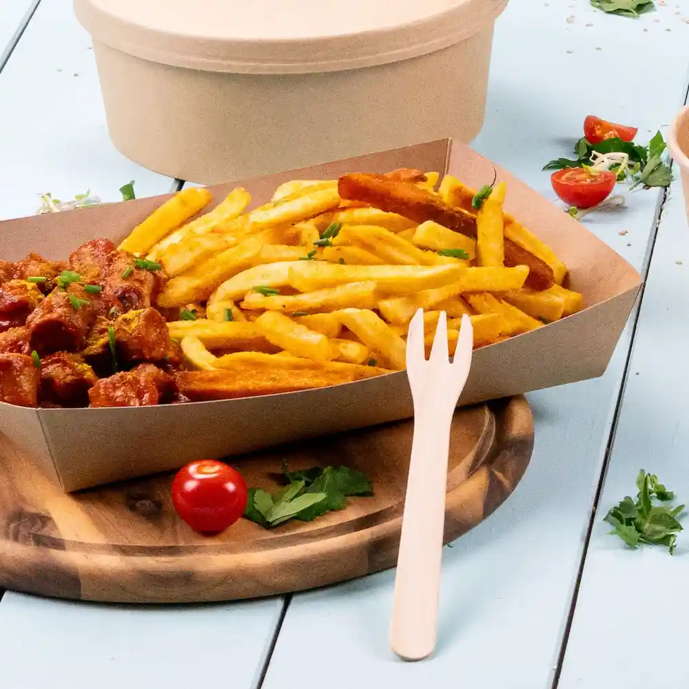 Portie frietjes met worst in saus, gegarneerd met kruiden, vergezeld van een houten vork op een houten plank.
