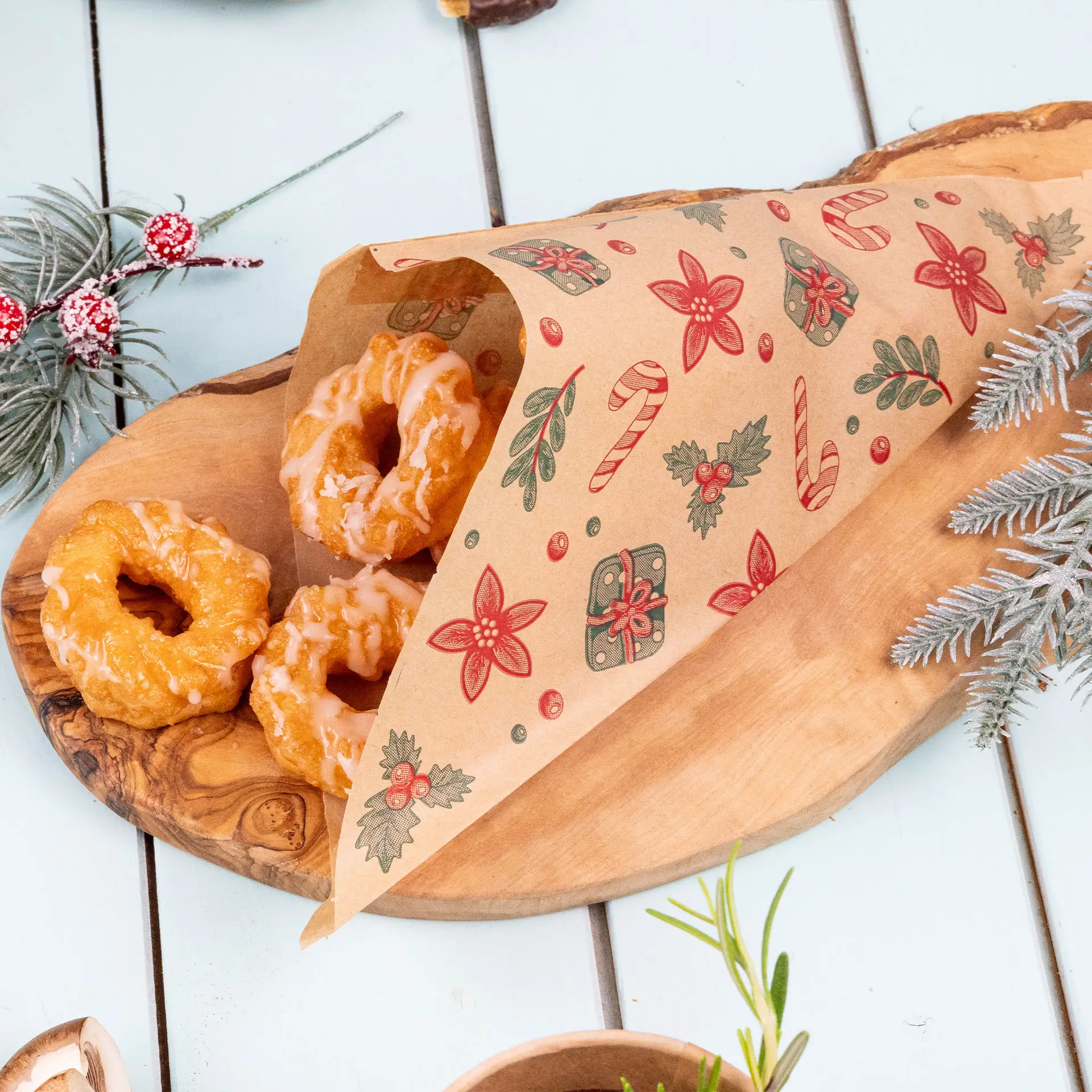 Bruine vetvrije tas met winterontwerp, met drie geglazuurde donuts op een houten schaal.