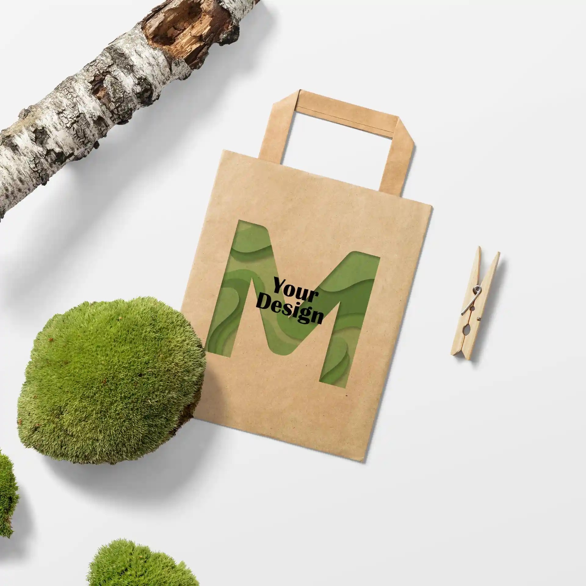 Bruine papieren draagtas in rechthoekige vorm met een uitsnede van de letter 'M' en de tekst 'Jouw Ontwerp'.