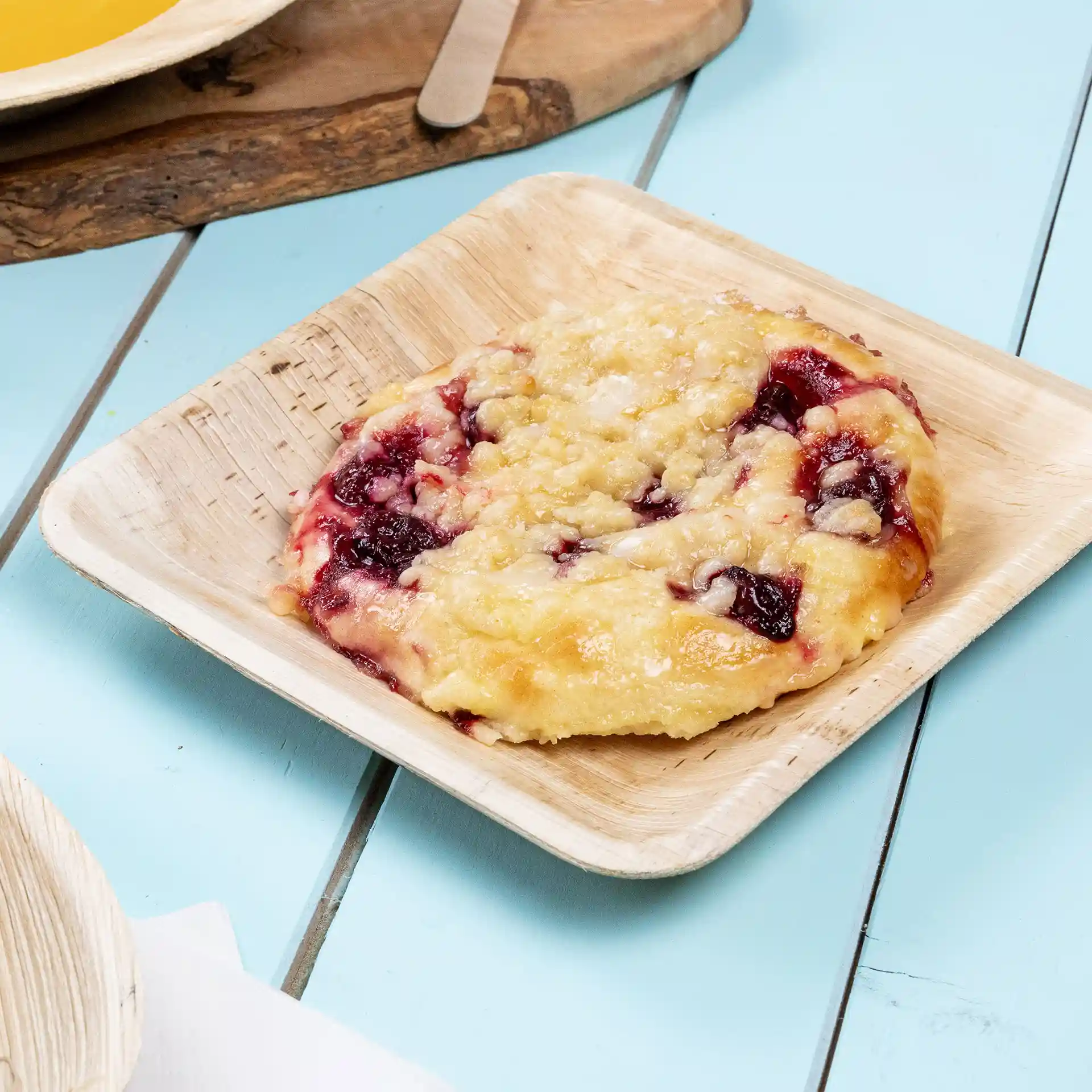 Vierkante palmbladplaat met een gebakje, belegd met fruitvulling en kruimeltopping.