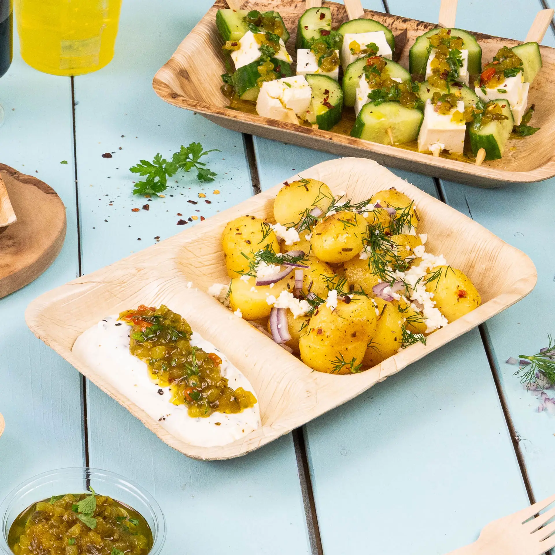 Rechthoekig palmbladmenu bord met drie compartimenten met kleurrijke voedingsmiddelen, waaronder groenten en dips.
