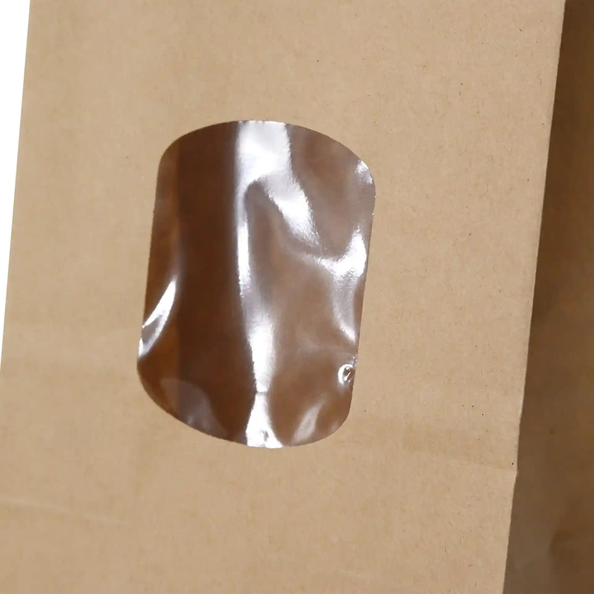Bruine kraftpapieren tas met een transparant PP-venster, met een tin tie sluiting, 8,5 x 5 x 24 cm groot.