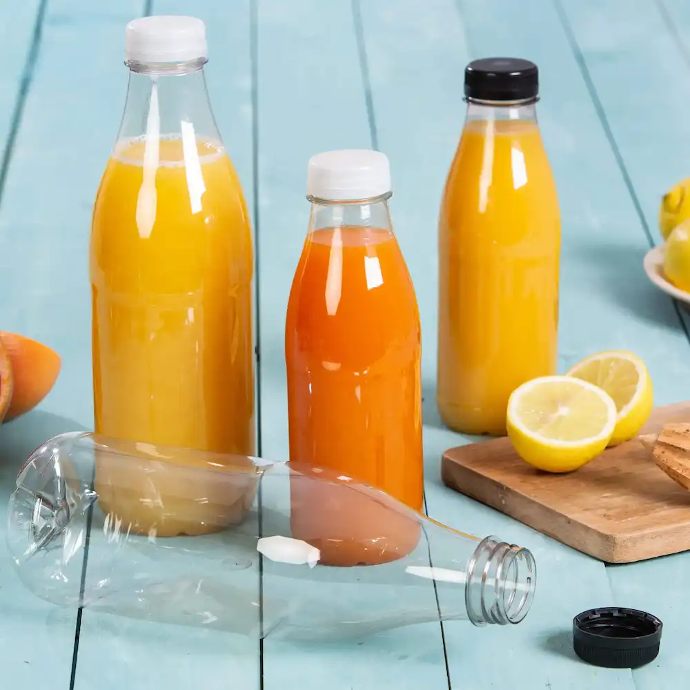Drie plastic flessen gevuld met gele en oranje sappen, één fles ligt, en een citroen en koekjes zijn in de buurt.