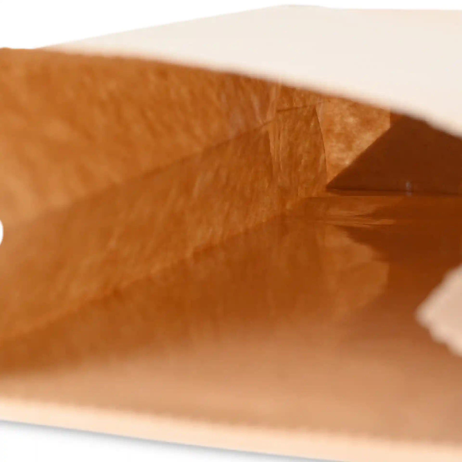 Interieur van een bruine kraftpapier blokbodemzak met een metalen sluiting, die de diepte en textuur van de zak toont.