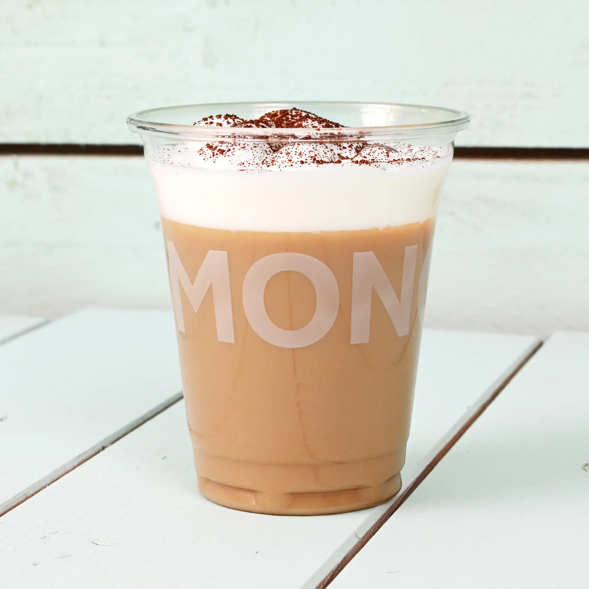 Doorzichtige 8 oz rPET beker gevuld met iced coffee, getopt met slagroom en cacao, op een houten oppervlak.