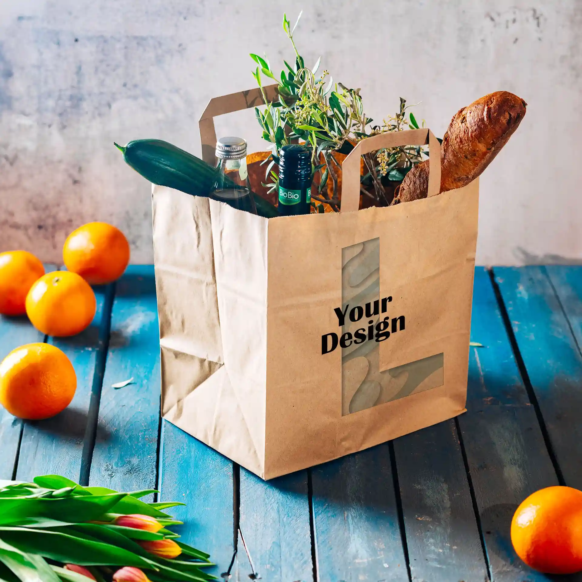 Bruine papieren draagtas met een brede bodem, gevuld met groenten, flessen en een baguette, op een blauwe houten ondergrond.