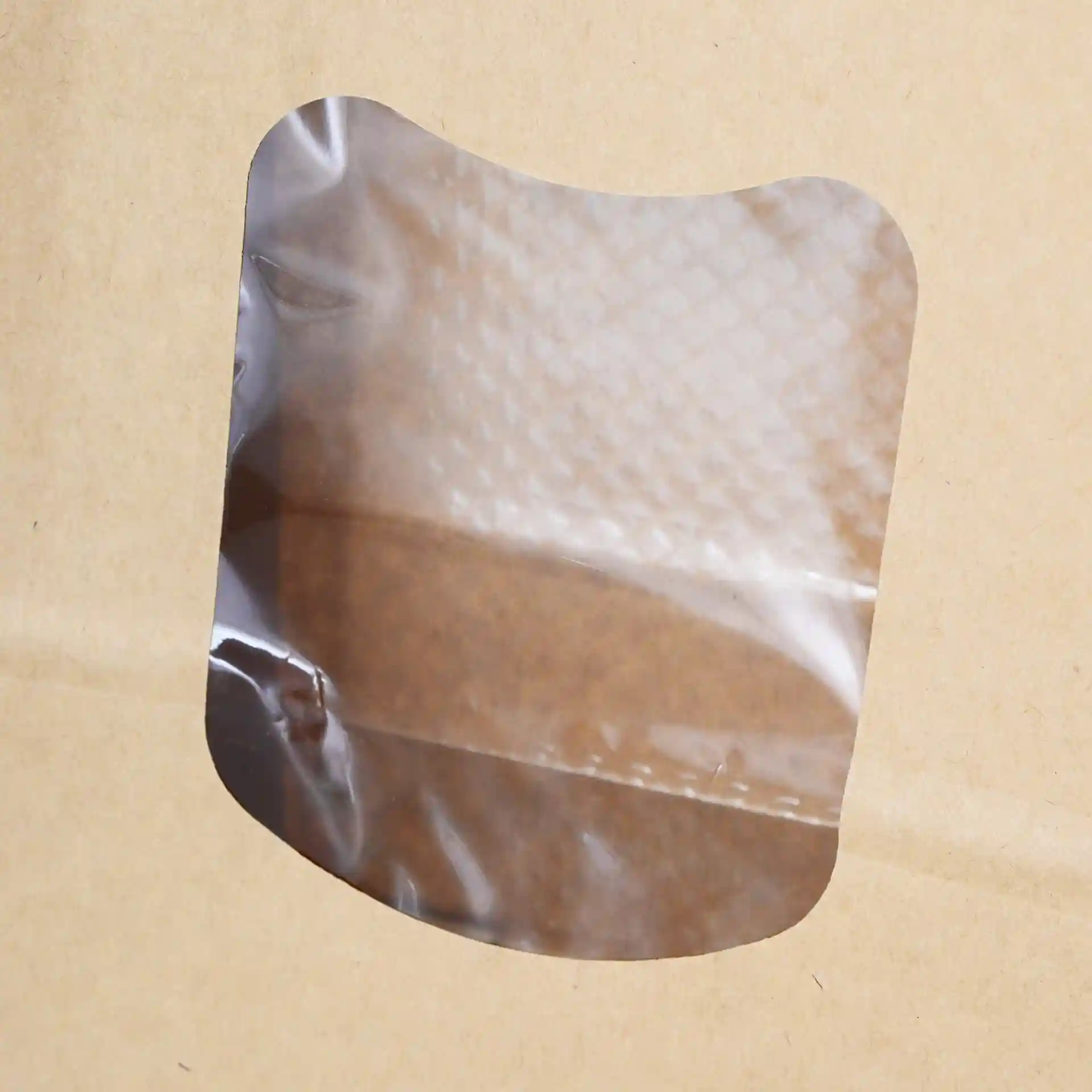 Transparant kijkvenster op een bruine kraftpapieren tas met afgeronde hoeken.
