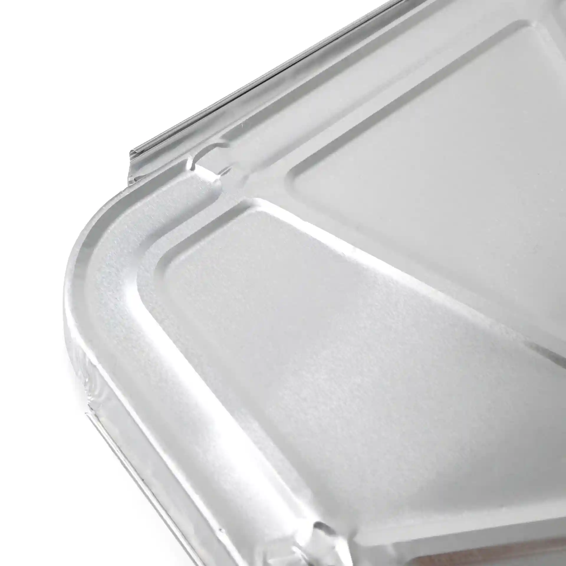 Aluminium deksel voor een rechthoekige maaltijdtray met twee compartimenten, close-up van het oppervlak en de randen.