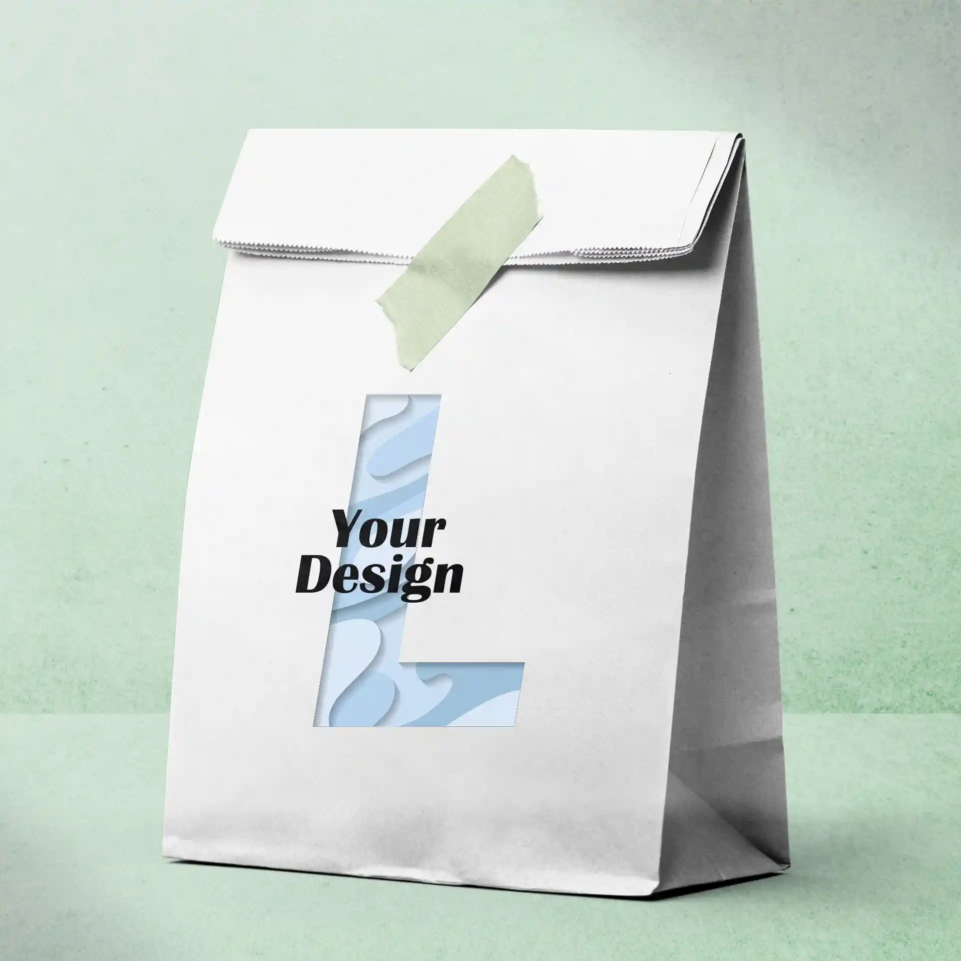 Witte papieren tas met uitgesneden letter 'L' en de tekst 'Jouw Ontwerp', vastgezet met groene tape.