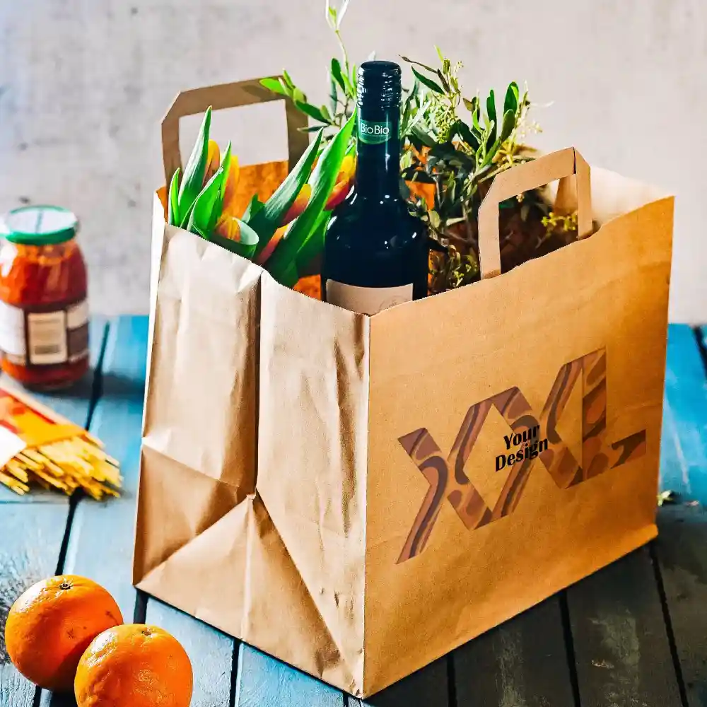 Bruine papieren tas met handvatten, met een wijnfles, bloemen en een pot, op een houten oppervlakte met sinaasappels.