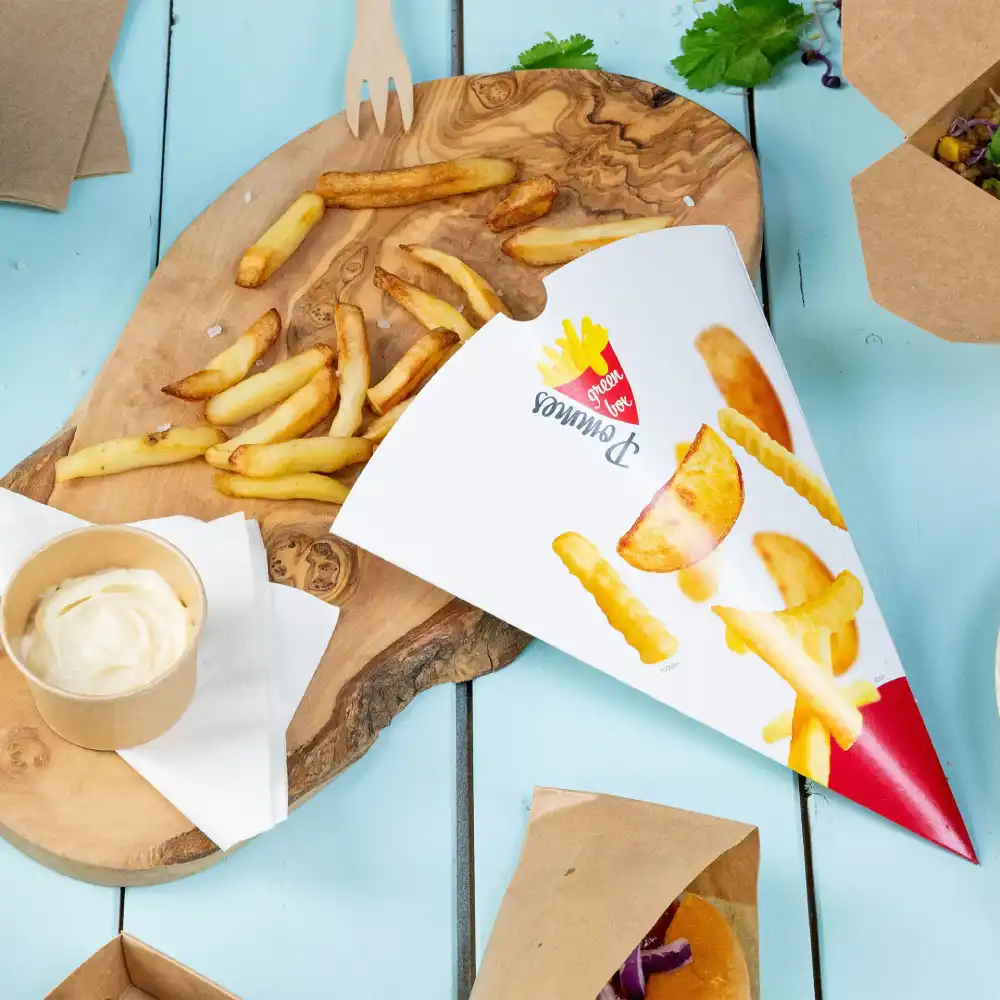 Tray met frieten in een cone, een klein bekertje dipsaus en extra frieten op een houten plank.