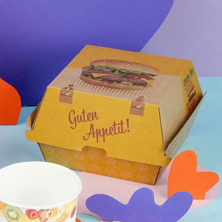 Bruine en witte burgerdozen met de tekst "BURGER", een hamburger met sesamzaadbrood en frietjes op een houten oppervlak.