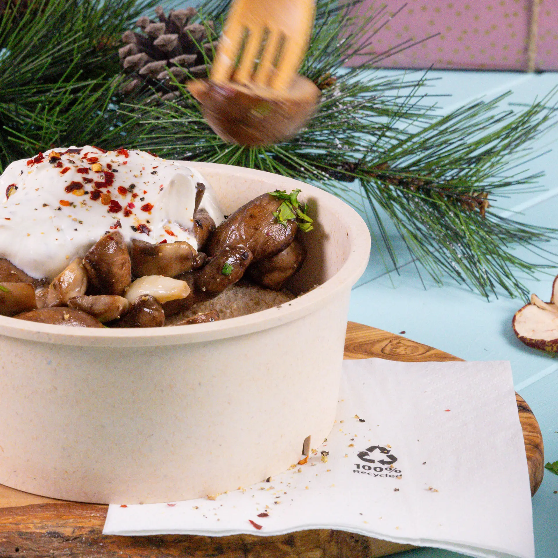 Vers bereid gerecht in een bruine kartonnen kom, gegarneerd met yoghurt, kruiden en specerijen; vergezeld van een witte gerecycleerde cocktailservet.