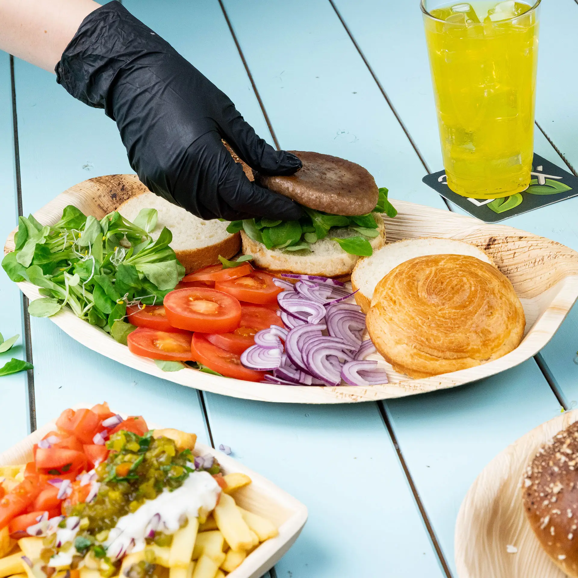 Een palmblad dienblad met drie sneetjes brood belegd met roomkaas en diverse vruchten, vergezeld van een yoghurtparfait en drankjes.