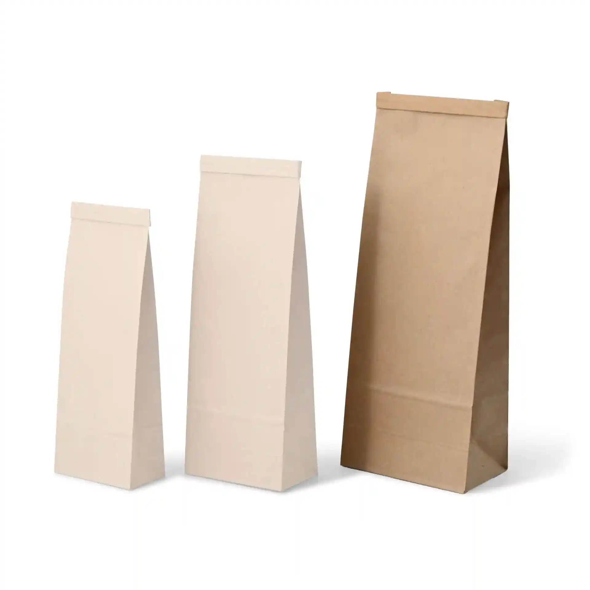Drie blokbodemzakken in verschillende maten, twee in crème en één in bruin kraftpapier, met platte bovenkanten.