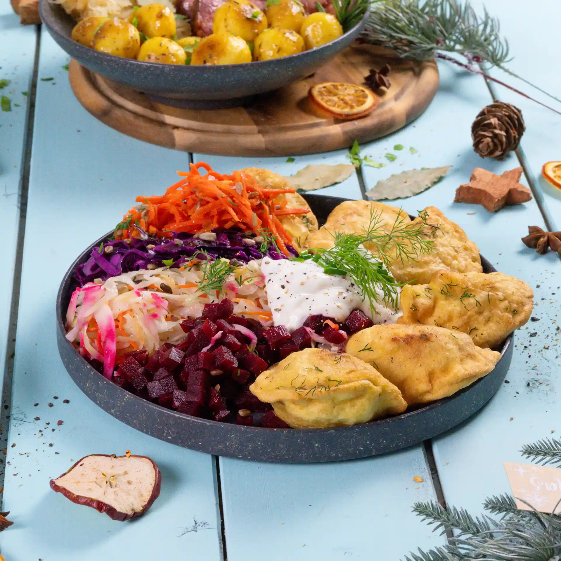 Ronde grijze herbruikbare plaat gevuld met verschillende kleurrijke salades, dips en gefrituurde items, op een blauwe ondergrond.