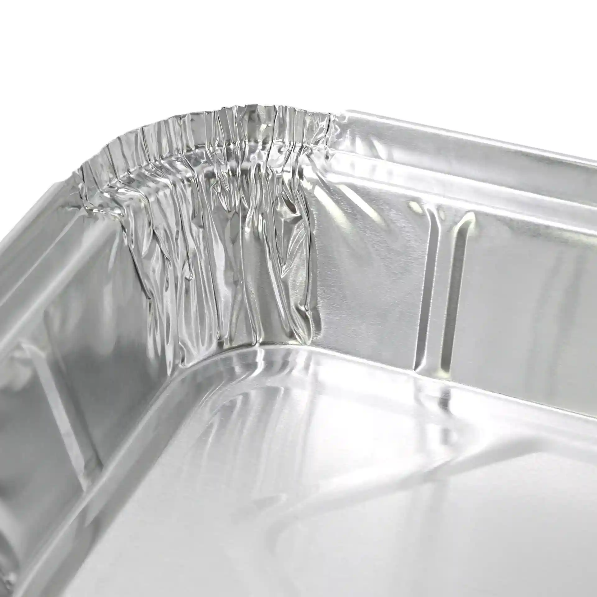 Close-up van de hoek van een rechthoekige aluminium container, met de gekrulde rand en glanzende oppervlakte.