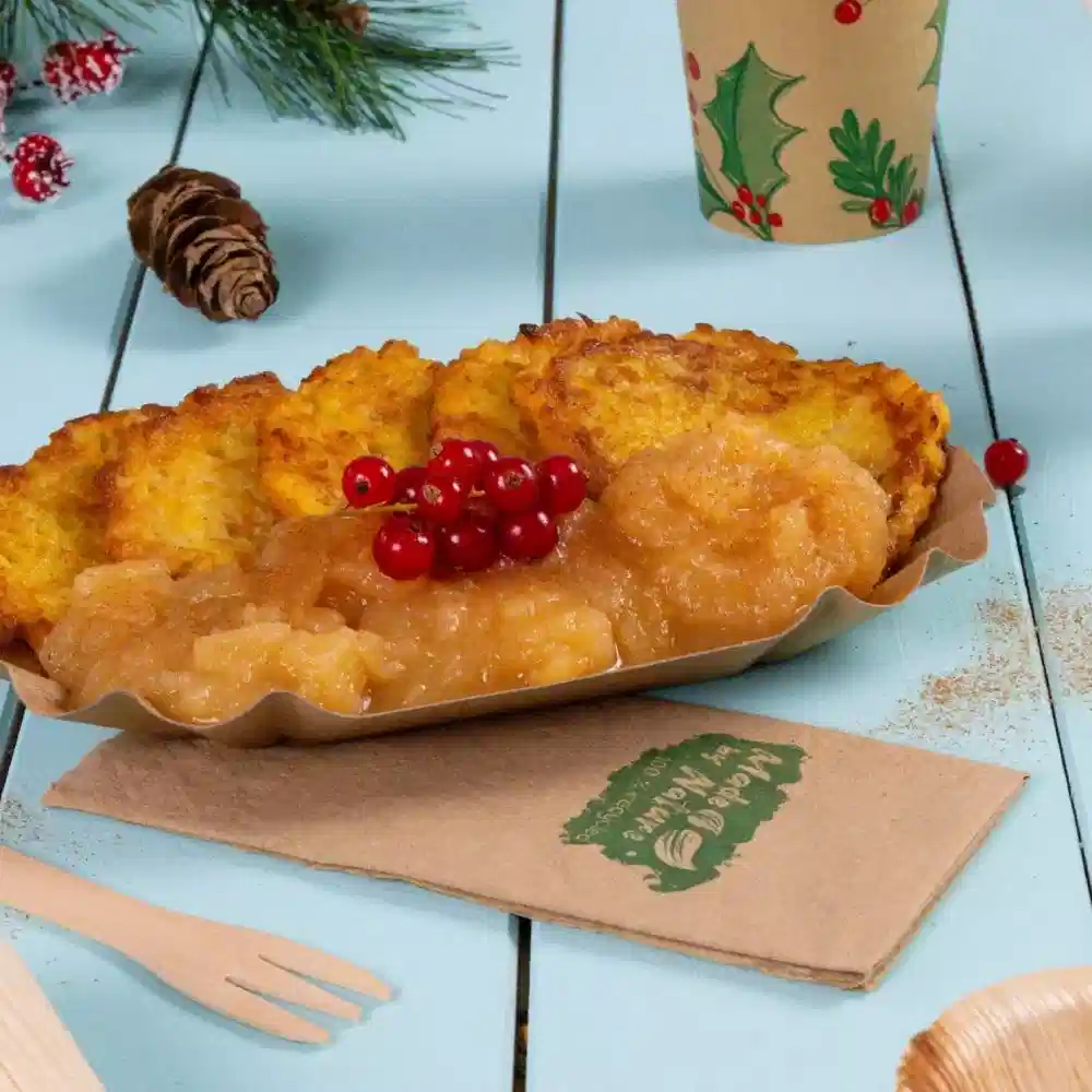 Een bord knapperige goudbruine gefrituurde aardappelkoekjes, geserveerd met appelmoes en rode bessen, op een blauwe houten tafel.