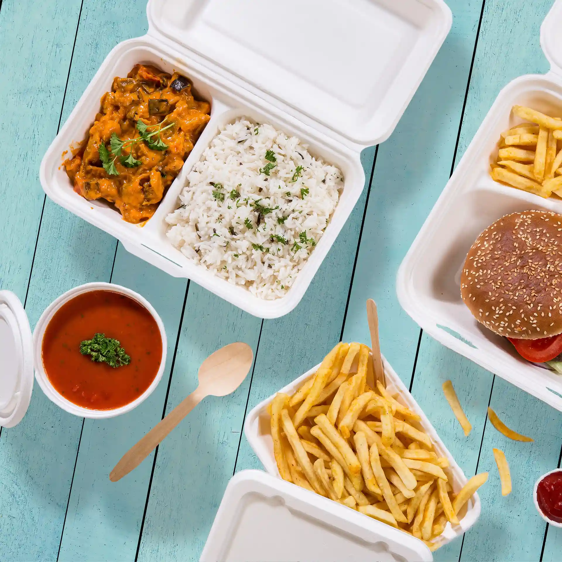Afbeelding van een crème-witte suikerrietcontainer met twee compartimenten, gevuld met rijst, curry, friet en een hamburger.