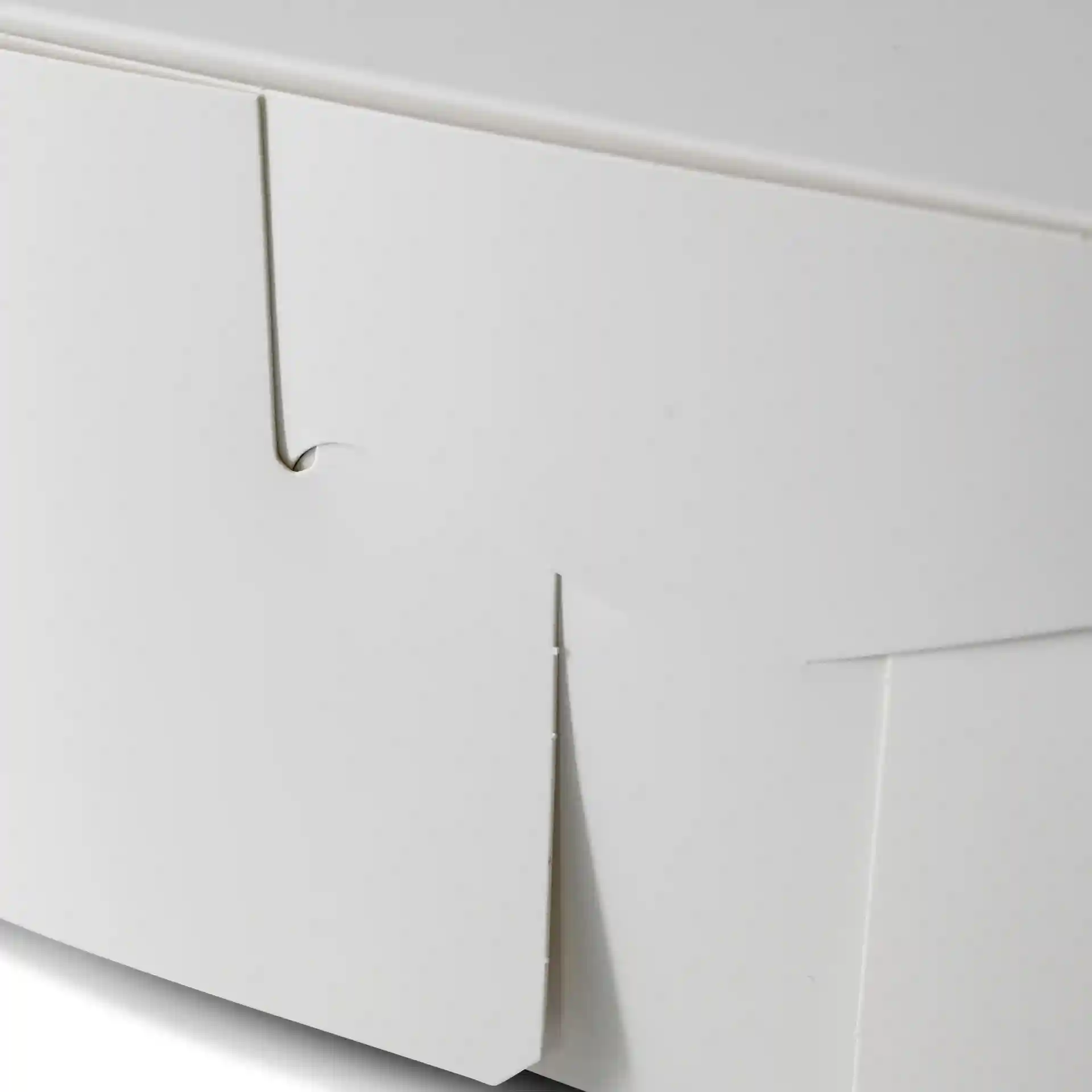 Close-up van een witte taartdoos met een omgevouwen flap, die de rand- en hoekdetails toont.