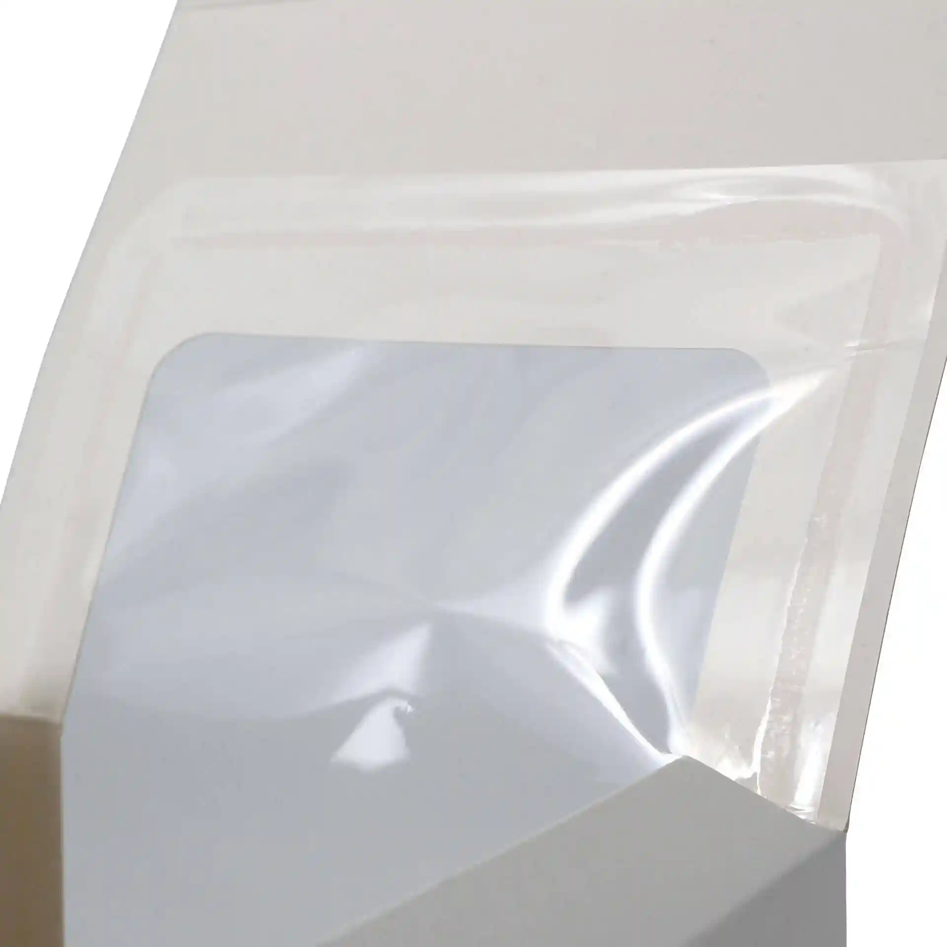 Close-up van een witte gebakdoos met een helder cellulosevenster, dat de opening en de binnenkant van de doos toont.